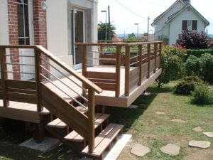 Holzterrasse mit Geländer und Treppe am Haus, ideal für Garten und Außenbereich.